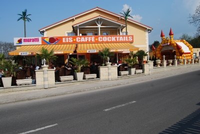 Muratti Gelateria in Gloggnitz von außen: gelbes Haus mit Schriftzug „Eis · Caffè · Cocktails“, Palmen und Gastgarten