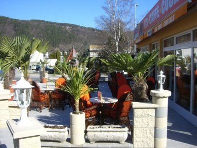 Gastgarten mit Palmen, Laternen und Korbsesseln